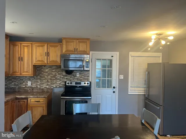 a kitchen with stainless steel appliances granite countertop a refrigerator a stove and a sink with wooden floor