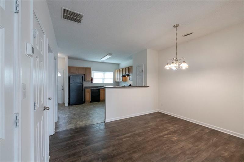 6045 Capitol Knoll Fairburn, GA 30213 - Photo 12 of 37 an empty room with wooden floor and kitchen view