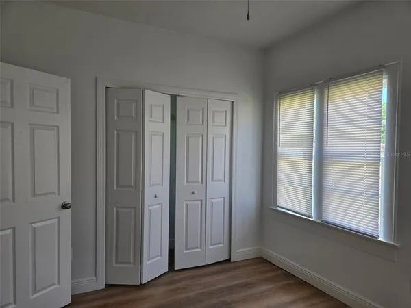 a view of an empty room with wooden floor and a window