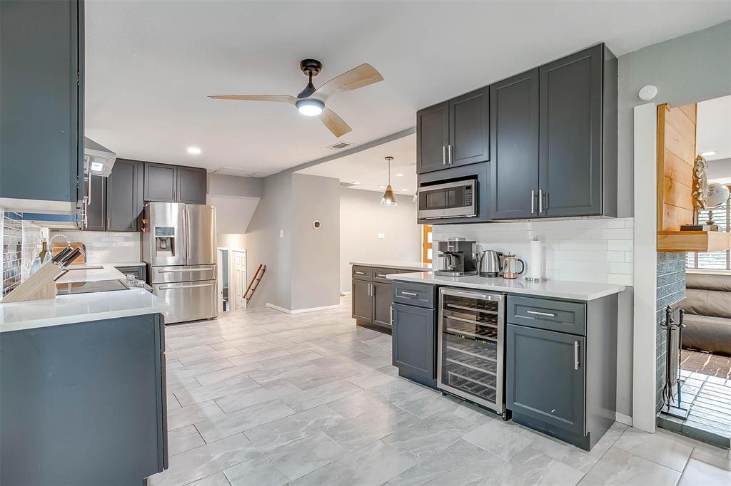 6609 Genoa Road Fort Worth, TX 76116 - Photo 12 of 39 Kitchen with beverage cooler, appliances with stainless steel finishes, ceiling fan, tasteful backsplash, and light countertops