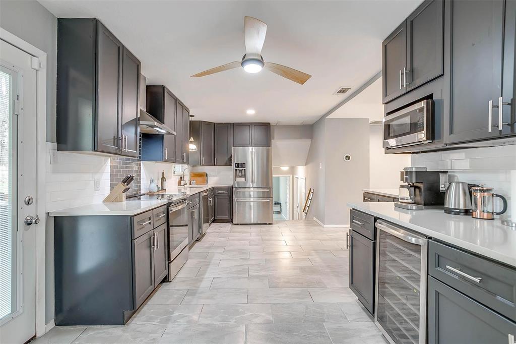 6609 Genoa Road Fort Worth, TX 76116 - Photo 13 of 39 Kitchen with appliances with stainless steel finishes, beverage cooler, ceiling fan, decorative backsplash, and light countertops
