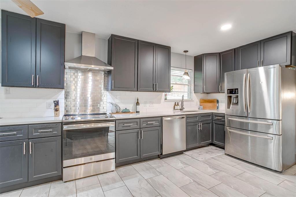 6609 Genoa Road Fort Worth, TX 76116 - Photo 14 of 39 Kitchen featuring stainless steel appliances, wall chimney exhaust hood, decorative backsplash, and light countertops