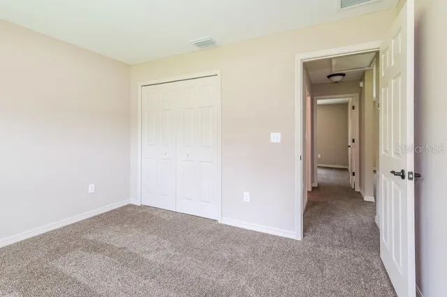 a view of an empty room with closet and a bathroom