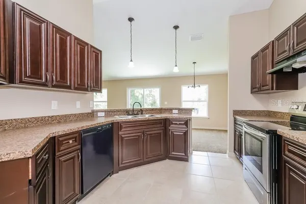 a kitchen with stainless steel appliances granite countertop a stove a sink dishwasher and a refrigerator with wooden cabinets