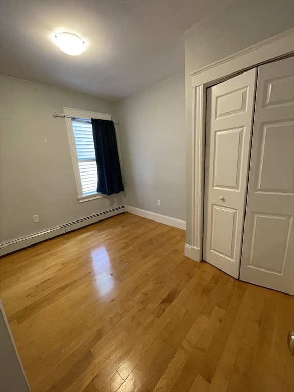 39 Calvin Street, Unit 2 Somerville, MA 02143 - Photo 4 of 11 an empty room with wooden floor and windows