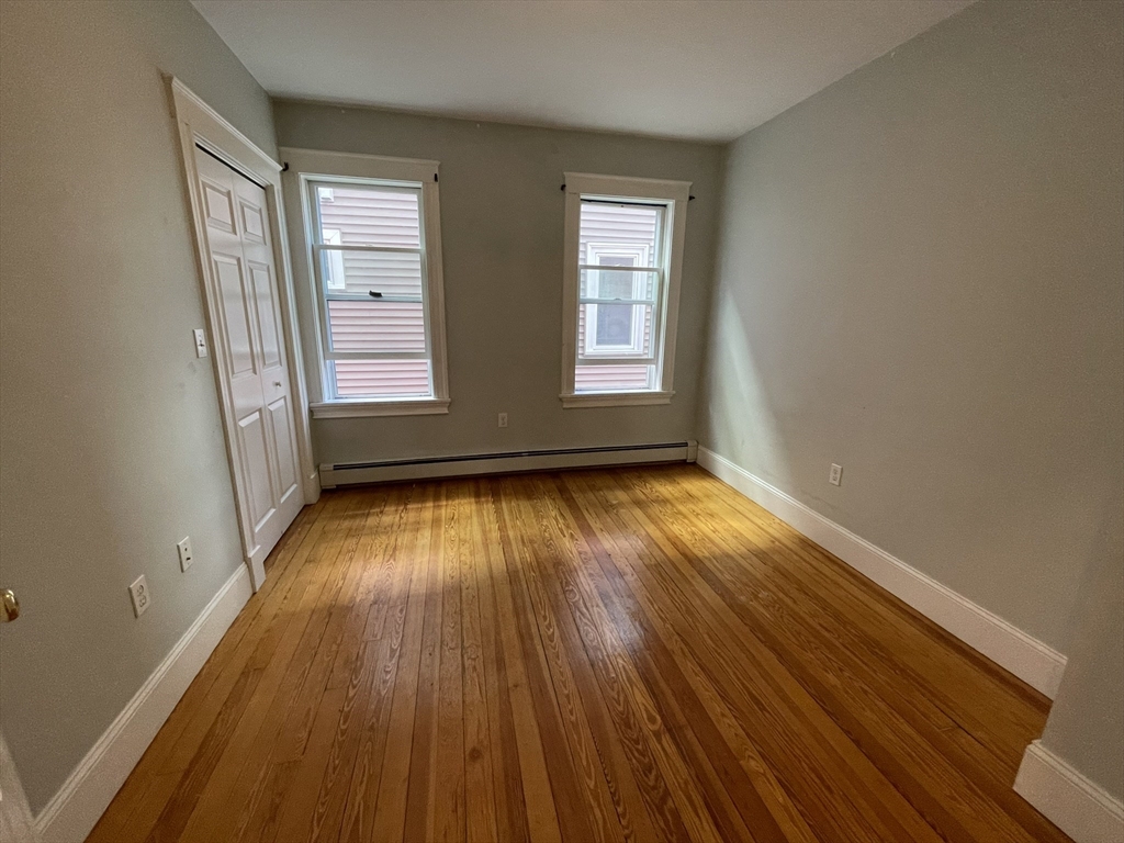39 Calvin Street, Unit 2 Somerville, MA 02143 - Photo 8 of 11 an empty room with wooden floor and windows