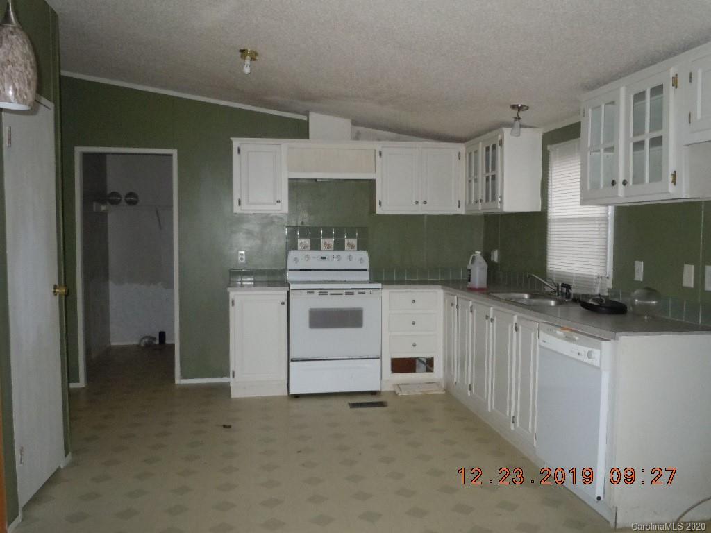 135 Austin Road Clyde, NC 28721 - Photo 3 of 9 a kitchen with white cabinets a sink stove and refrigerator