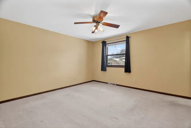 an empty room with windows and ceiling fan