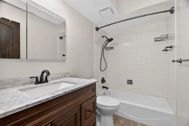 a bathroom with a granite countertop sink a toilet and shower
