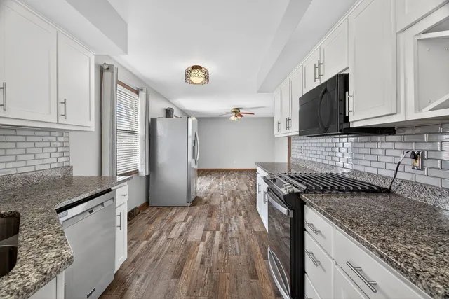 a kitchen with granite countertop a sink stove and refrigerator