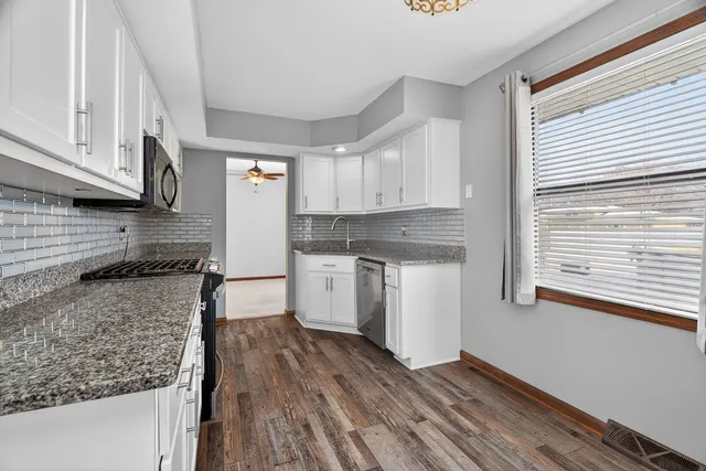 a kitchen with granite countertop wooden floors and white appliances