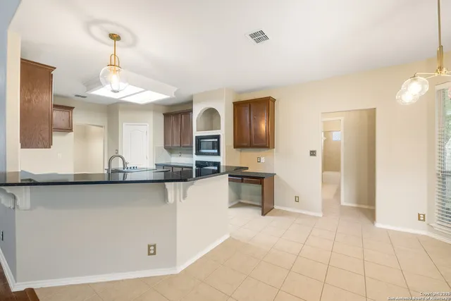 a kitchen with granite countertop a stove a sink and a refrigerator