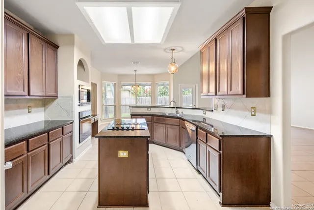a kitchen with stainless steel appliances granite countertop a sink counter space cabinets and a large window