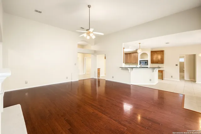 a view of empty room with wooden floor and kitchen view