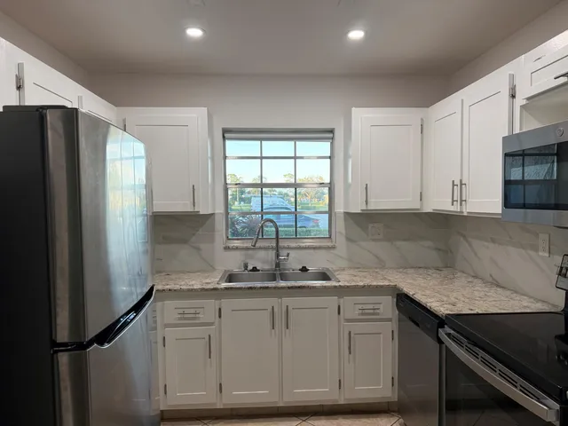 a kitchen with granite countertop a sink cabinets and stainless steel appliances
