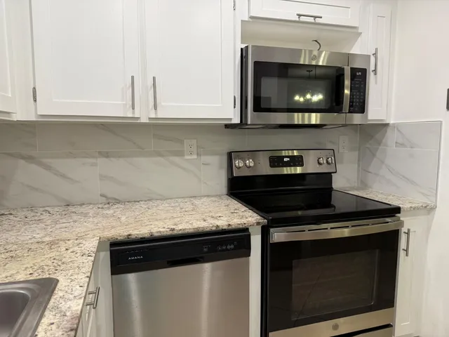 a kitchen with stainless steel appliances granite countertop a stove microwave and oven