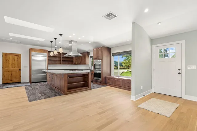 a large kitchen with stainless steel appliances kitchen island granite countertop a refrigerator and a stove top oven