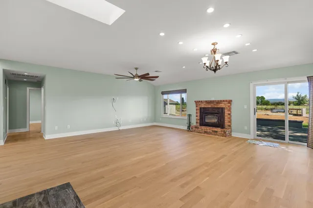 an empty room with fireplace chandelier and glass door