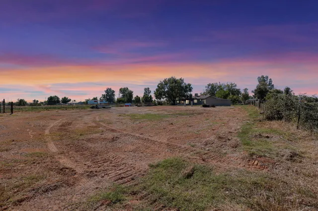 a view of a field with trees in background