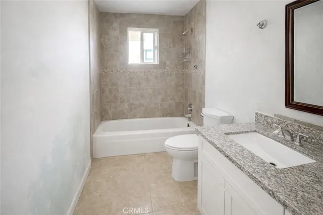 a bathroom with a granite countertop sink a toilet and bathtub