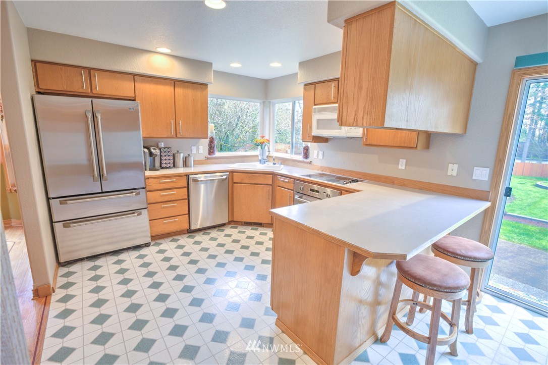 7736 Fairview Road Southwest Tumwater, WA 98512 - Photo 7 of 25 a kitchen with stainless steel appliances granite countertop a refrigerator a stove a sink and white cabinets with wooden floor
