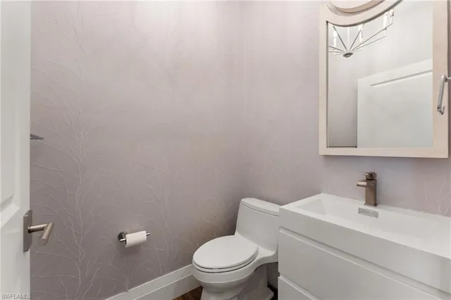 a large white kitchen with a sink and stainless steel appliances
