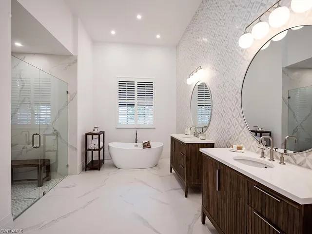 a spacious bathroom with double vanity sinks a large mirror and a bathtub