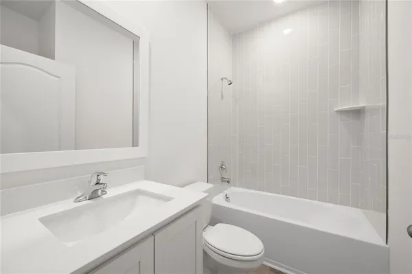 a bathroom with a bathtub shower sink vanity mirror and toilet