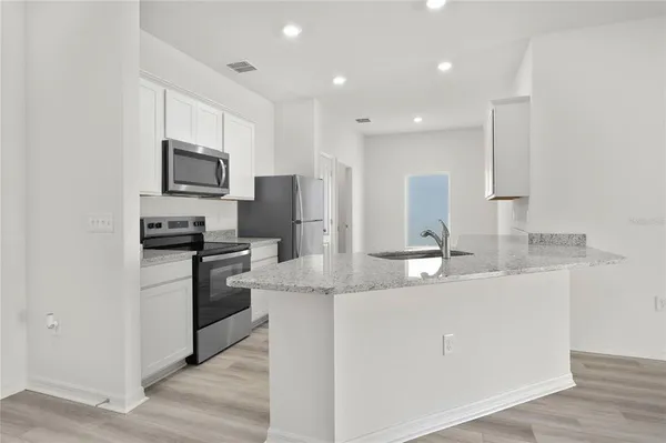 a kitchen with stainless steel appliances granite countertop a sink a stove a refrigerator a microwave and cabinets