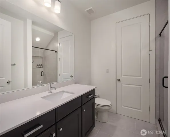 a bathroom with a sink a toilet a shower and a mirror