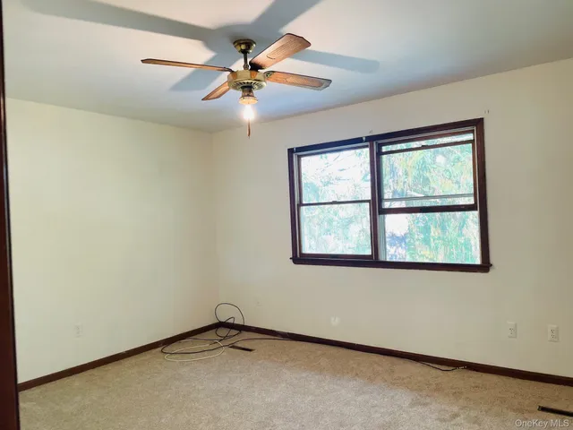 an empty room with a window and a fan