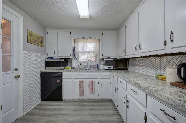 a kitchen with stainless steel appliances granite countertop a stove a sink and white cabinets
