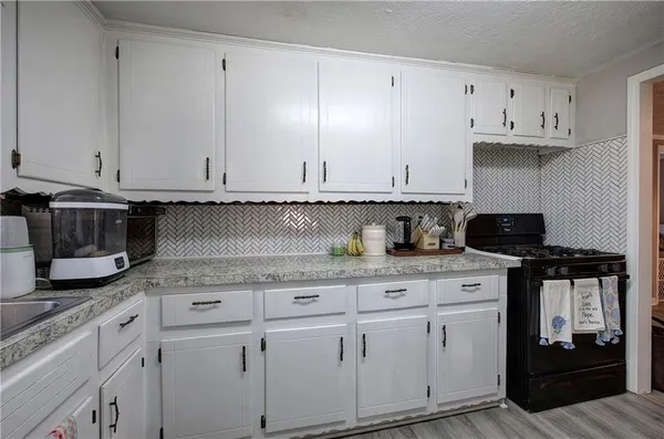 a kitchen with granite countertop a stove a sink and cabinets