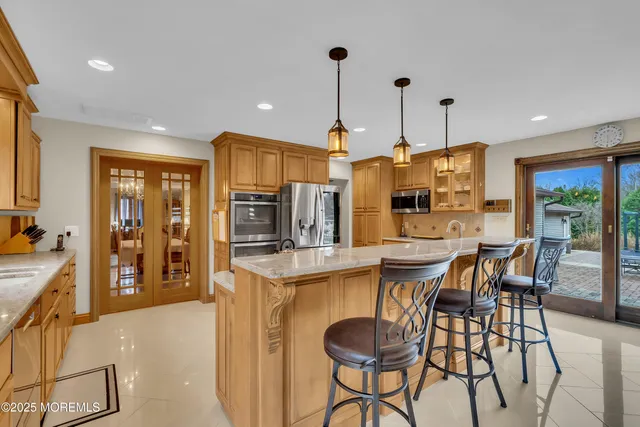 a kitchen with stainless steel appliances kitchen island granite countertop a refrigerator a stove a sink a dining table and chairs with wooden floor