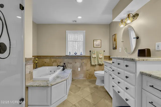 a bathroom with a granite countertop sink a mirror a toilet and a bathtub