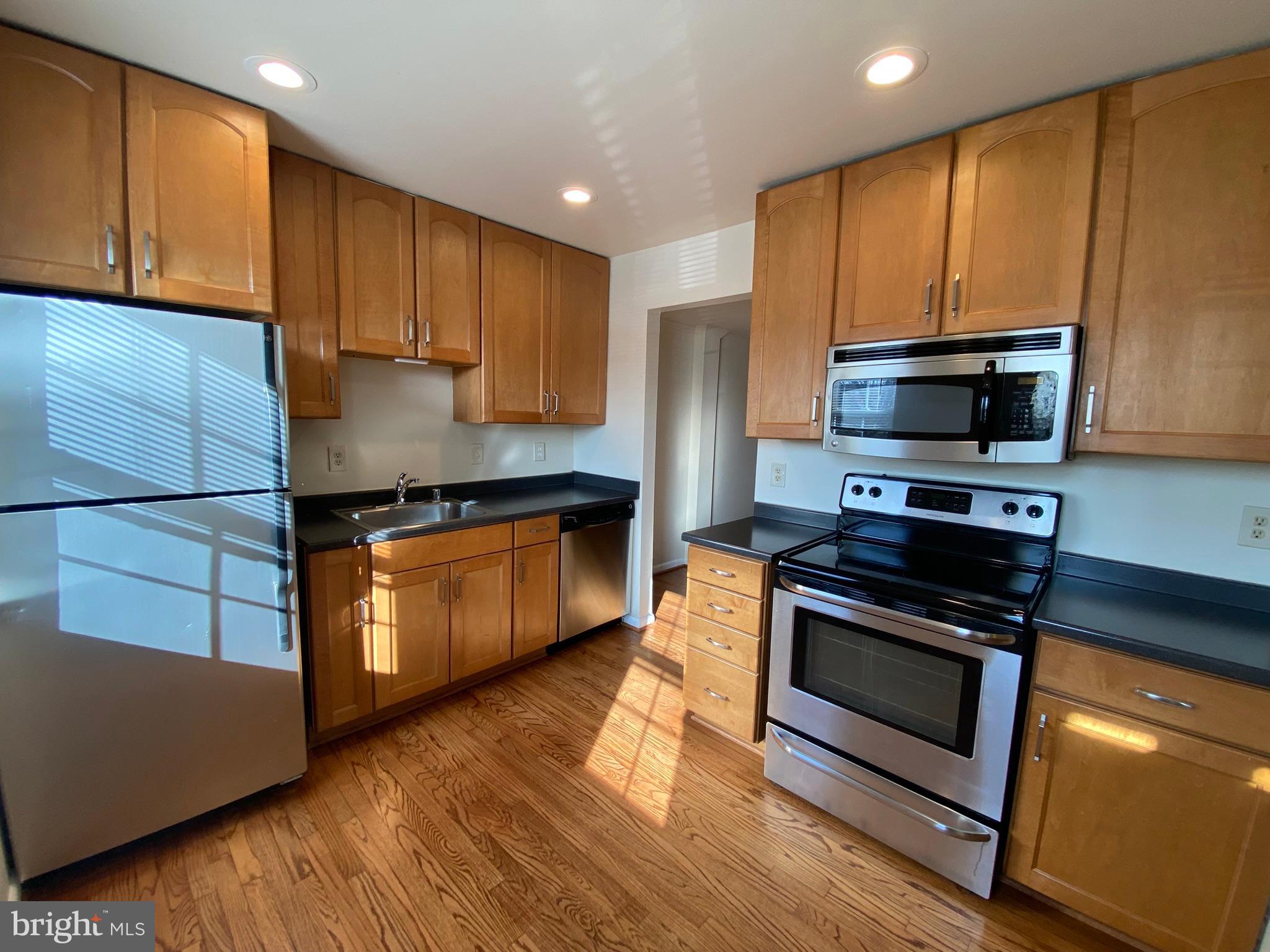 7432 Pohick Road Lorton, VA 22079 - Photo 3 of 27 a kitchen with wooden floors and stainless steel appliances