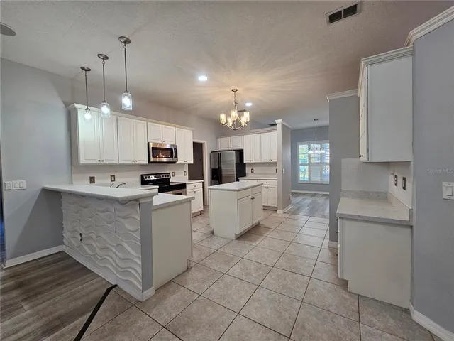 a kitchen with kitchen island granite countertop stainless steel appliances cabinets a sink and a counter top space