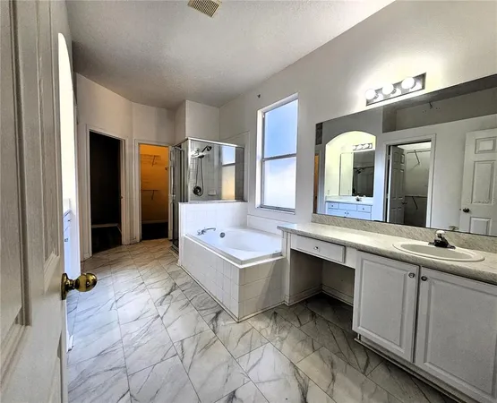 a spacious bathroom with a granite countertop sink mirror and bathtub