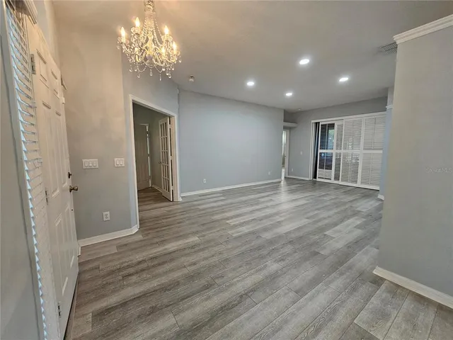 wooden floor in an empty room with a chandelier