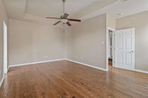 an empty room with wooden floor closet and fan