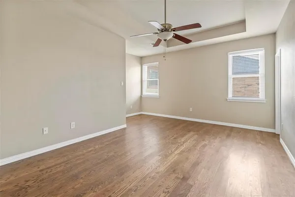 an empty room with wooden floor fan and windows