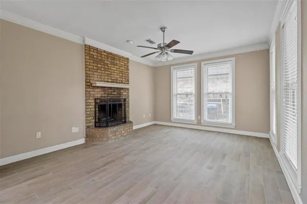 a view of an empty room with wooden floor fireplace and a window