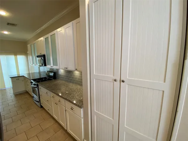 a kitchen with stainless steel appliances granite countertop a sink and a granite counter tops with white cabinets
