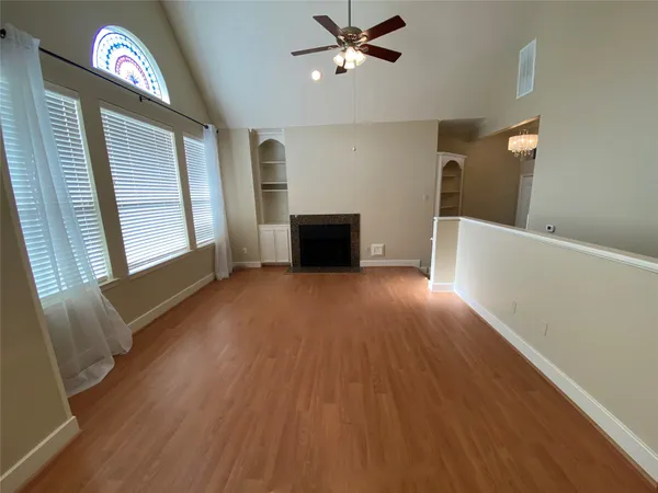 a view of empty room with wooden floor and fan