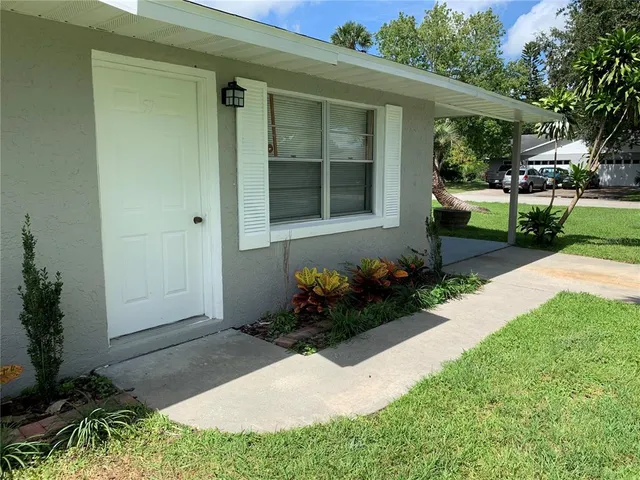 a front view of a house with a yard and potted plants