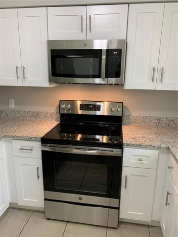 a kitchen with stainless steel appliances granite countertop grey cabinets a stove a sink and dishwasher