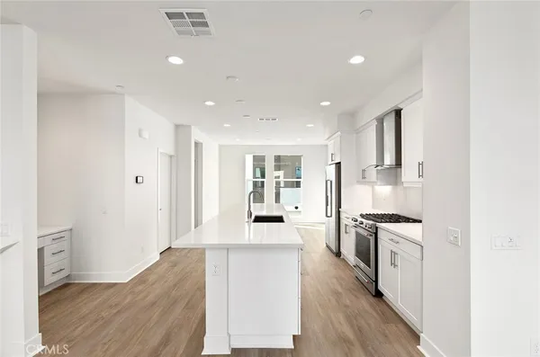 a large kitchen with stainless steel appliances granite countertop a lot of counter space and wooden floor