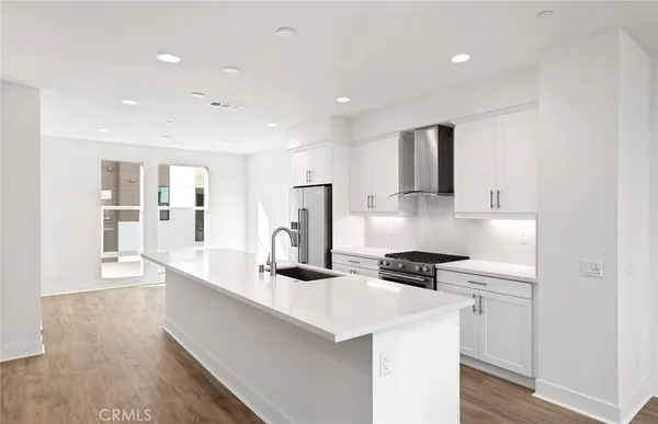 a kitchen view with stainless steel appliances kitchen island a sink a stove a refrigerator and cabinets