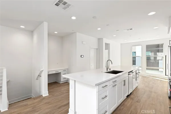 a large white kitchen with a sink and wooden floor