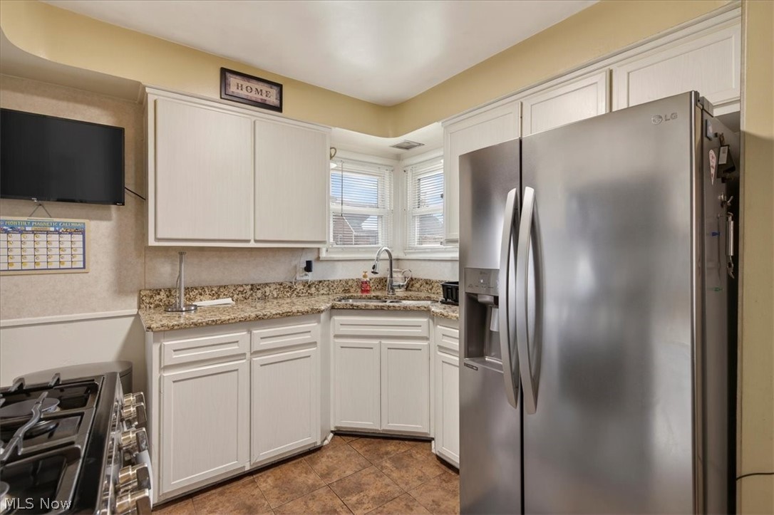 17282 McCracken Road Maple Heights, OH 44137 - Photo 5 of 26 Kitchen featuring stainless steel appliances, white cabinetry, and light stone countertops